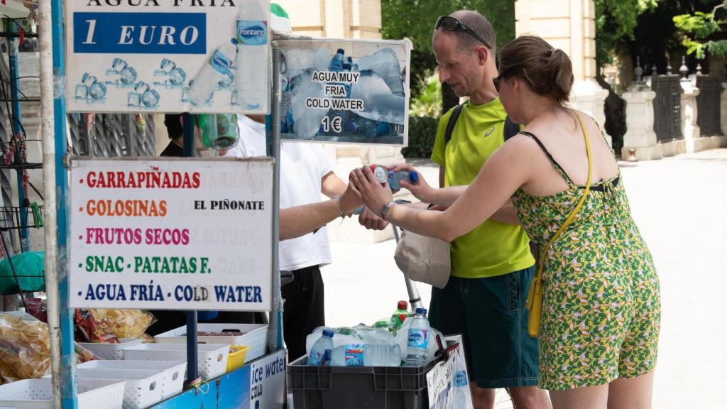 Unos turistas compran agua en un puesto callejero de la ciudad, a 19 de julio de 2024, en Sevilla.