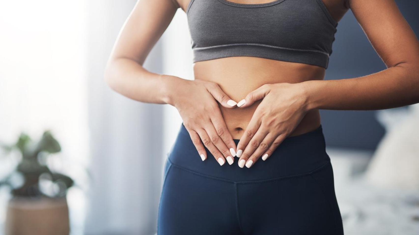 Mujer haciendo un corazón con las manos sobre su barriga.