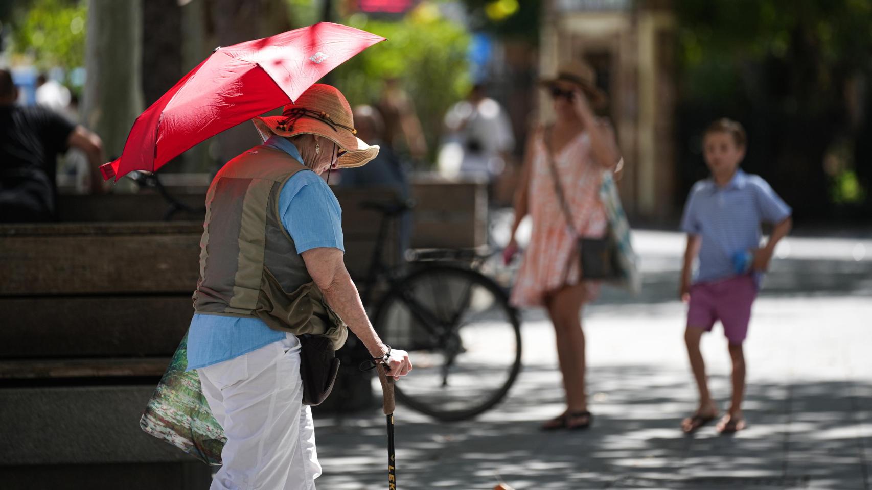 Una mujer se tapa con un paragüas en Sevilla.