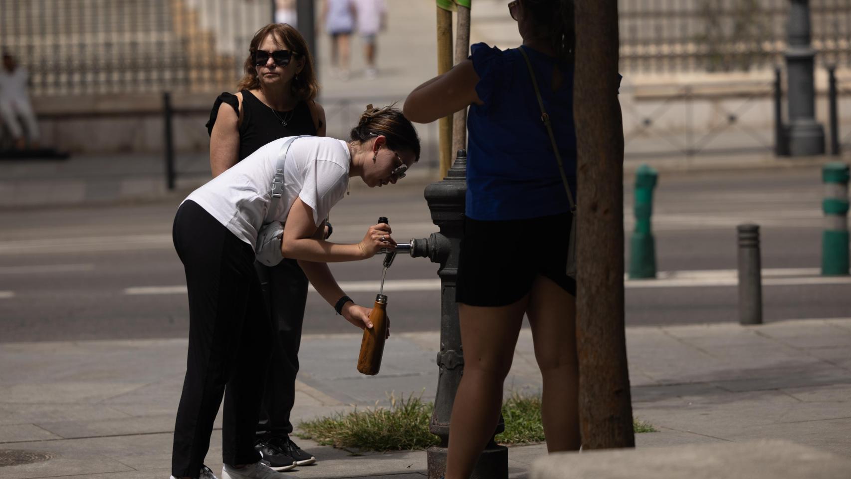 Una mujer rellena su botella en una fuente de Madrid.