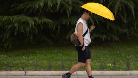 Un hombre se resguarda del sol bajo un paraguas, en Madrid.