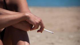 Una mujer fuma en la playa.