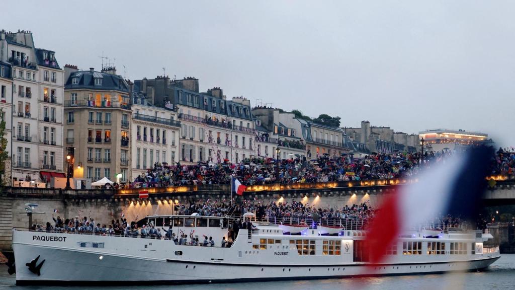 La delegación francesa en su enorme barco por el Sena saludan a los espectadores