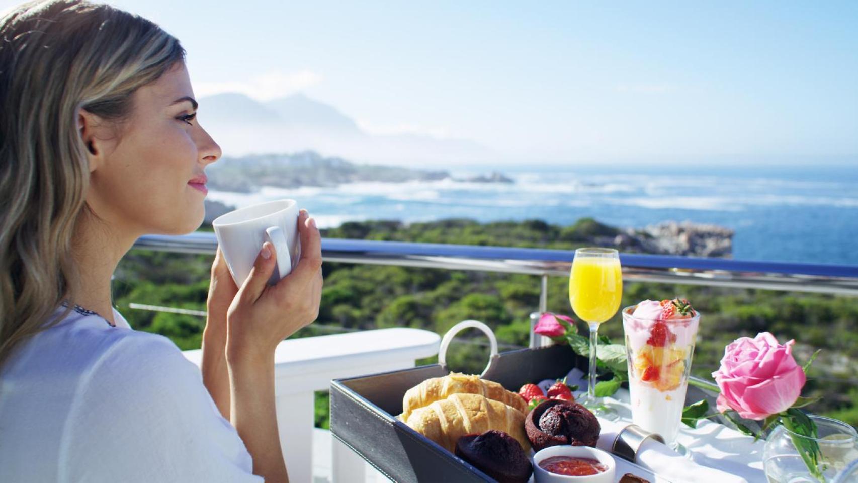 Mujer desayunando frente al mar.