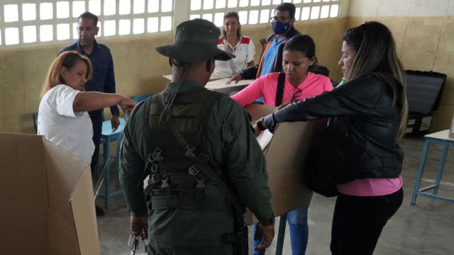 Un soldado da instrucciones a un voluntario que prepara una mesa electoral en un colegio de Caracas.