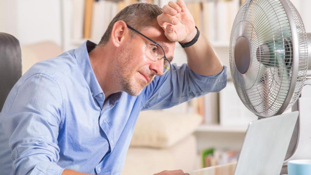 Imagen de archivo de un hombre pasando calor en la oficina.