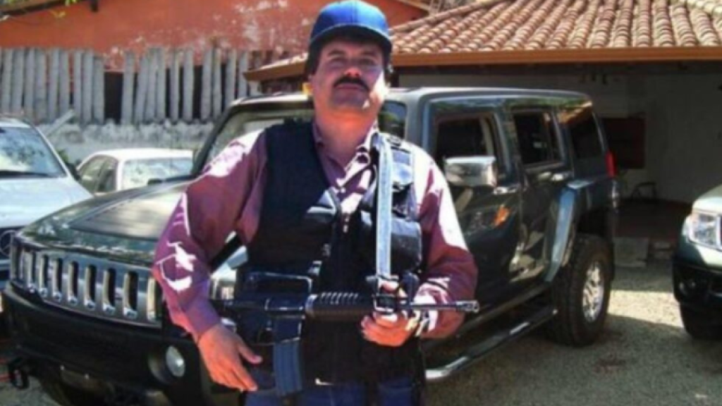 Ismael 'El Mayo' Zambada porta un arma pesada junto a un coche de alta gama.