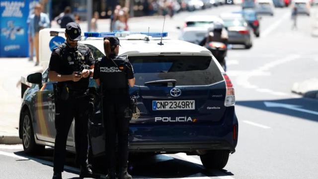 Una pareja de la Policía Nacional junto al coche patrulla en una céntrica calle.