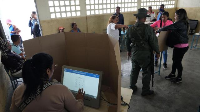 Un soldado y voluntarios preparan una mesa electoral en una escuela de Caracas, antes de las elecciones presidenciales.