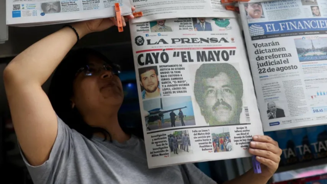 Una mujer coloca en un kiosko de la Ciudad de México un periódico que lleva en portada la detención de 'El Mayo'.