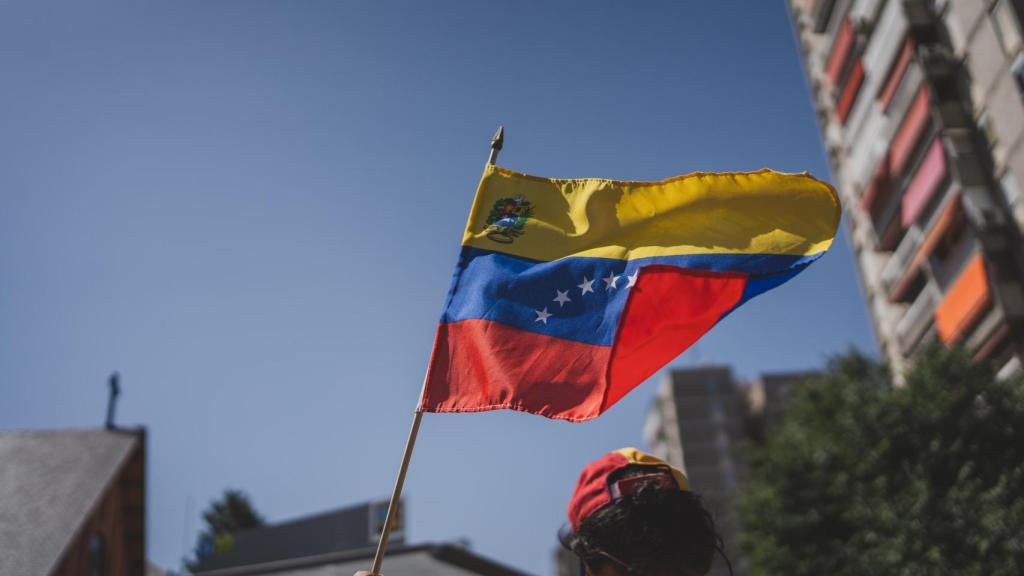 Un elector alza al aire la bandera de Venezuela.