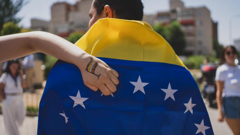 Una joven muestra su mano, con la bandera de Venezuela dibujada, mientras otro porta la bandera a modo de capa.