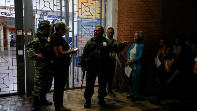 Un personal de seguridad gesticula mientras voluntarios entran en un centro de votación en Caracas.