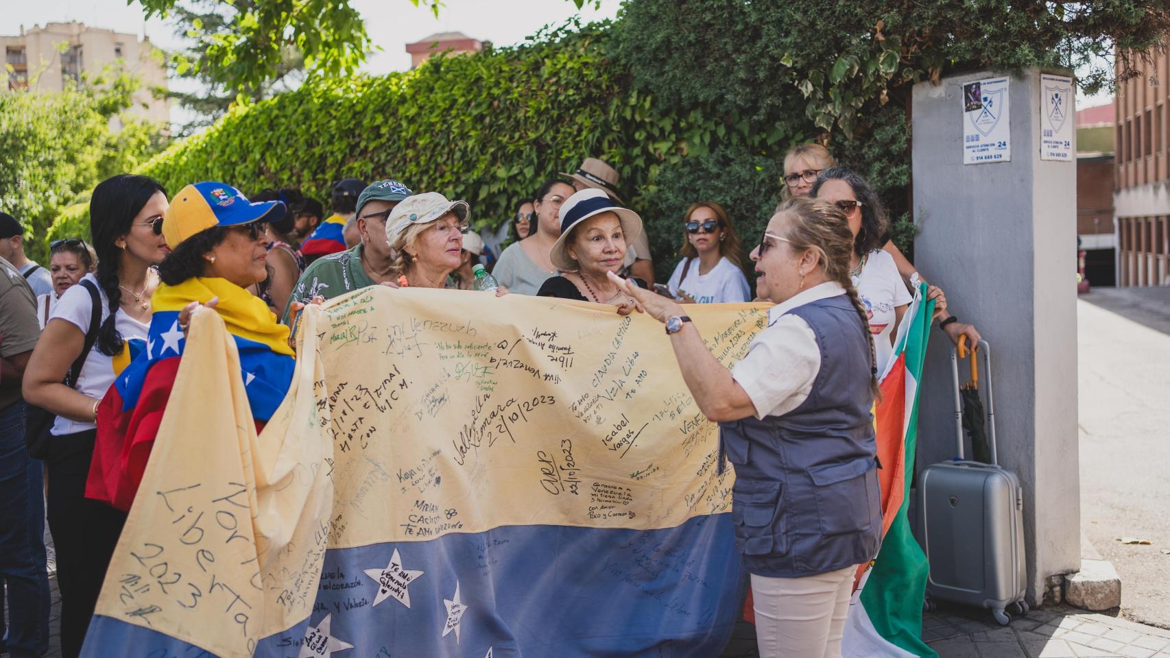 Un grupo de personas se manifiestan frente al centro de votación elegido por el Consulado de Venezuela en Madrid.