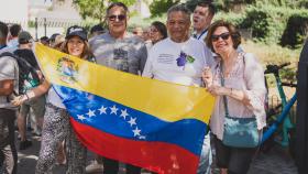 Erick sostiene la bandera de Venezuela junto a otros compatriotas a las puertas del Centro Cultural Fernando de los Ríos, donde no pudo ejercer su derecho al voto.