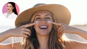 Mujer con sombrero aplicándose protector solar en la cara.