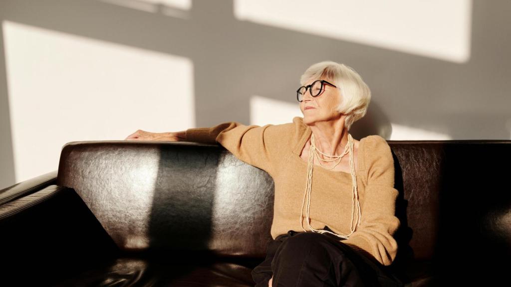 Mujer mayor de pelo blanco sentada al sol