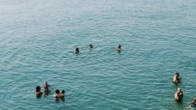 Veraneantes bañándose en la playa que está a los pies del chiringuito Saam
