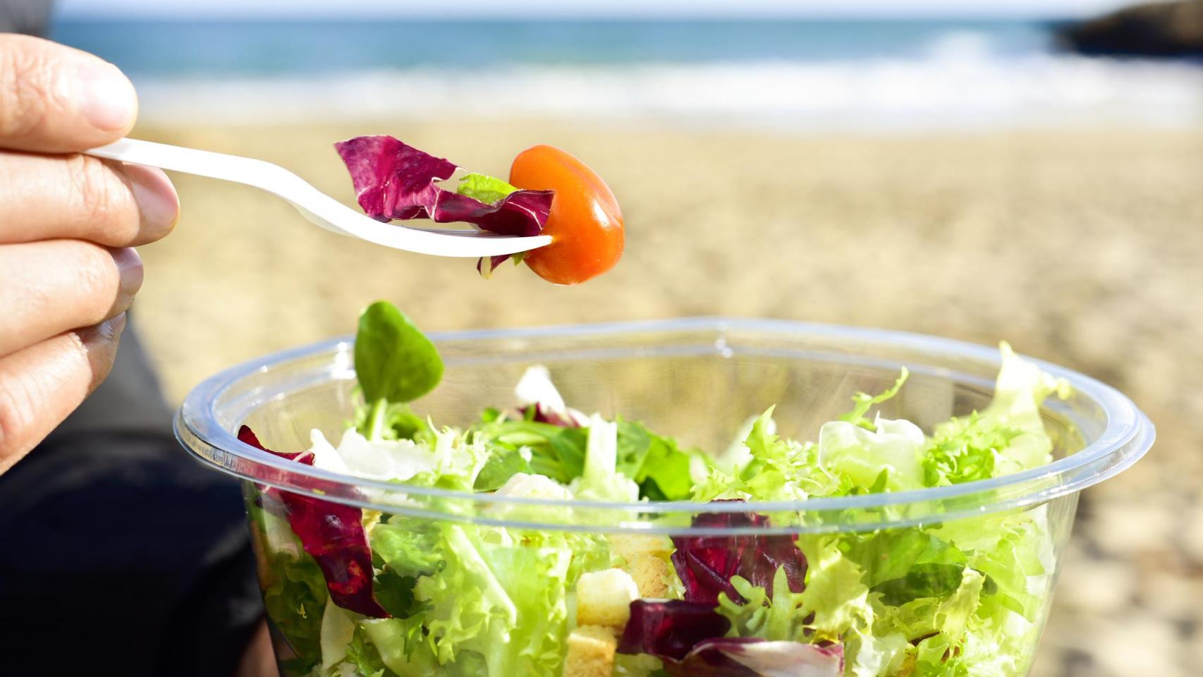 Una persona come una ensalada en la playa