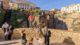 Un turista se sube a un murete para conseguir una foto del tajo de Ronda, Málaga.