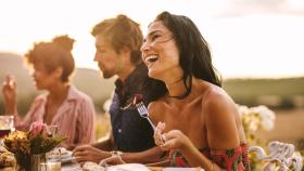 Mujer riendo en una comida con amigos.