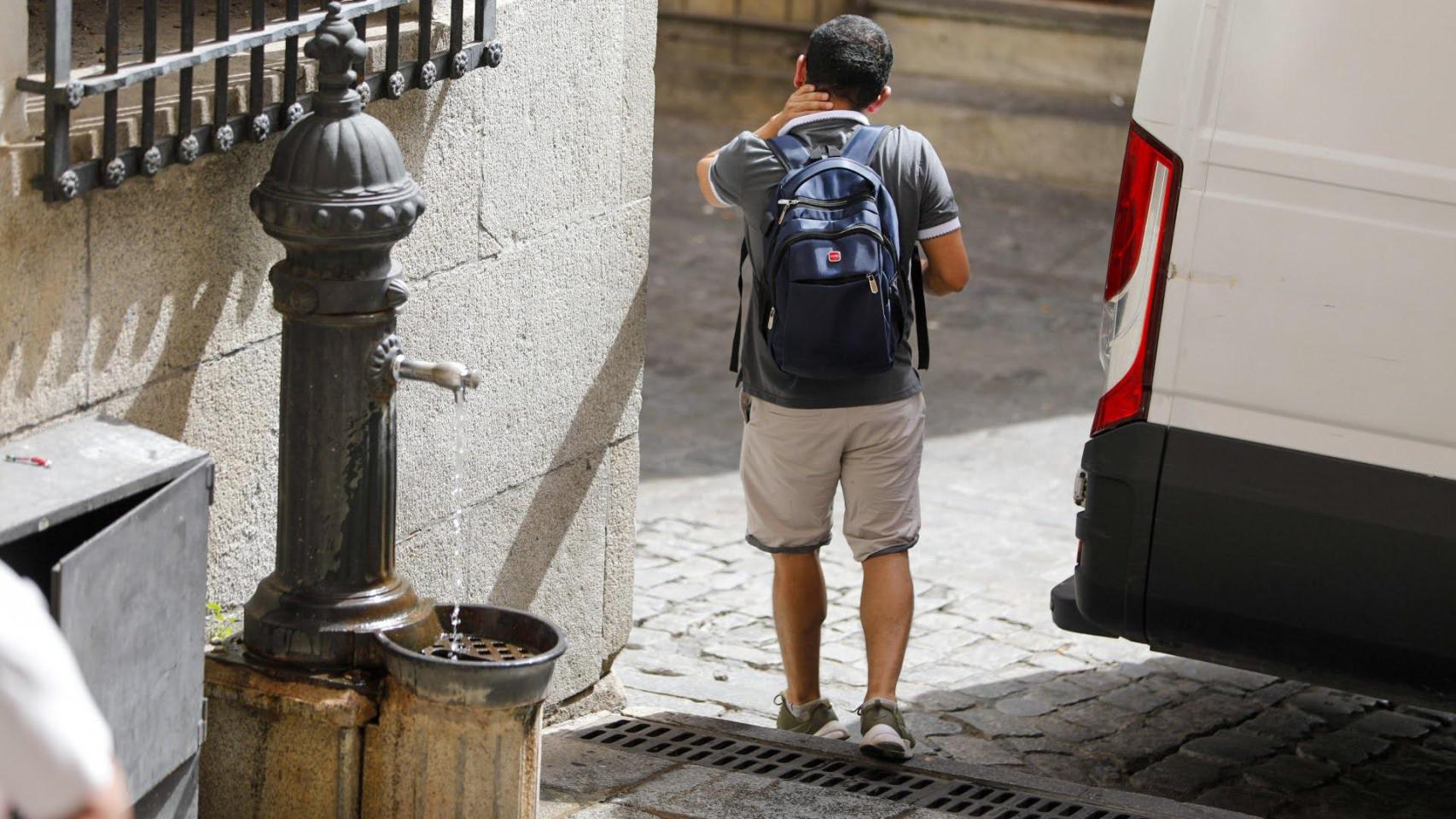 Un hombre después de refrescarse en una fuente pública.