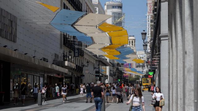 Varias personas caminan por una calle del centro de Madrid durante una ola de calor de agosto de 2023.