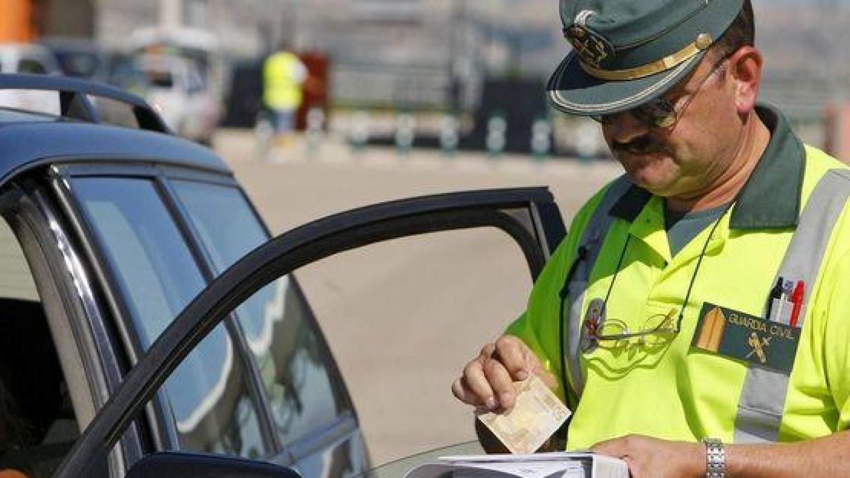 Un Guardia Civil pone una multa a un conductor.