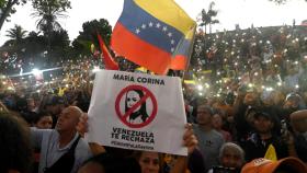 Seguidores de Nicolás Maduro muestran carteles en contra de María Corina Machado, en Caracas.