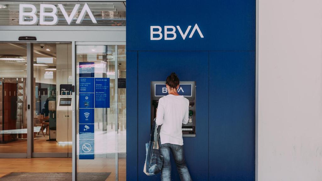 Una mujer retira dinero de un cajero de BBVA.