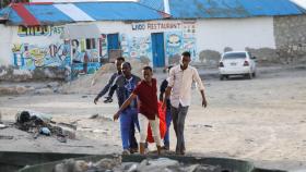 Las personas llevan el cuerpo sin vida de una mujer no identificada que murió en una explosión que ocurrió mientras los festejadores nadaban en la playa Lido en Mogadiscio, Somalia, el 3 de agosto de 2024.