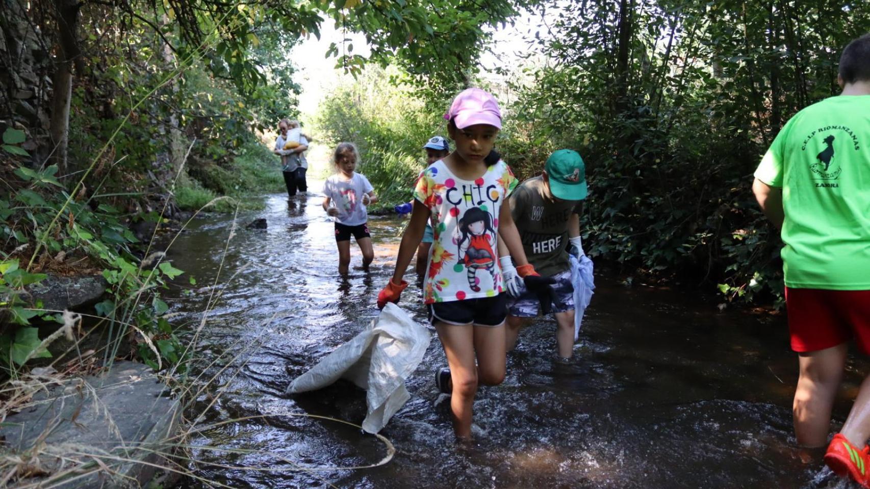 Varios niños participan en la limpieza de la orilla del río