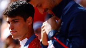Carlos Alcaraz, durante la ceremonia de las medallas en París 2024, y en primer plano Novak Djokovic