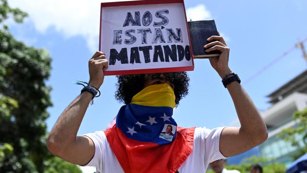 Un partidario de la oposición venezolana sostiene un cartel que dice 'Nos están matando', en la manifestación en Caracas.