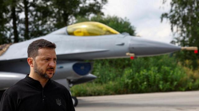 El presidente de Ucrania, Volodímir Zelenskiy, habla con los medios frente a un avión de combate F-16 después de conmemorar el Día de las Fuerzas Aéreas de Ucrania el  4 de agosto de 2024.