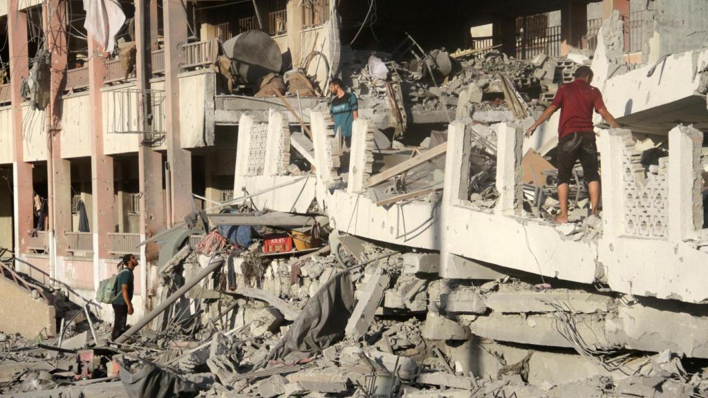 Los palestinos inspeccionan el lugar de los ataques israelíes contra una escuela que alberga a personas desplazadas, en medio del conflicto entre Israel y Hamas, en la ciudad de Gaza.