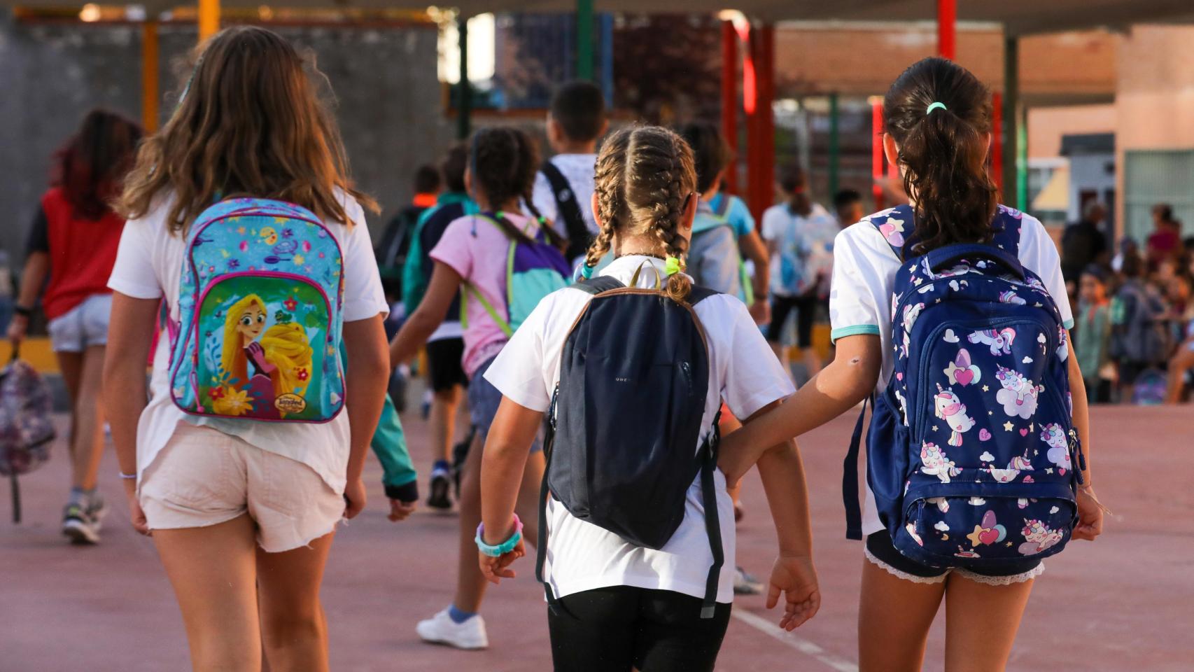 Imagen de archivo de tres niños en la entrada de un colegio.