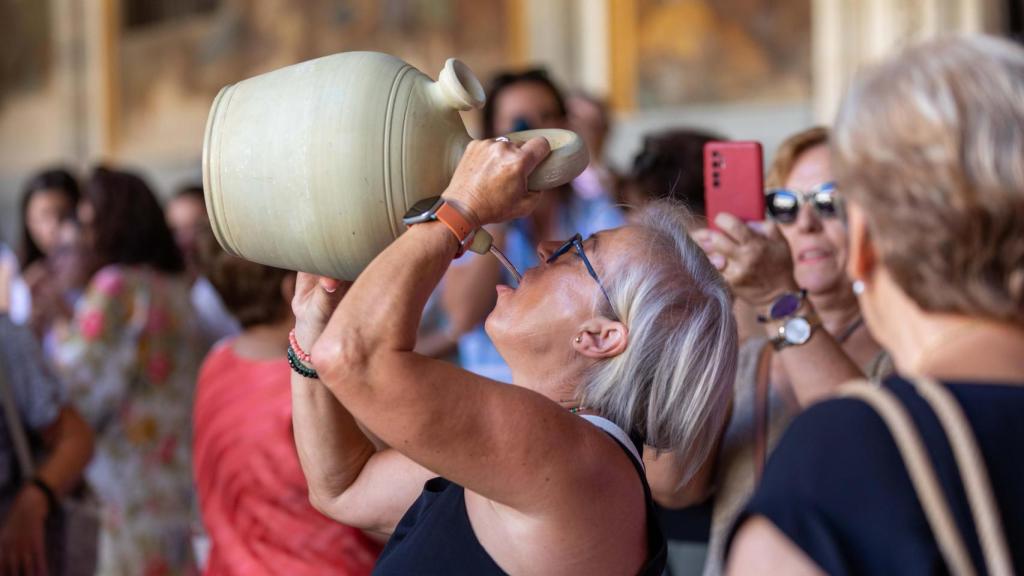 Una toledana cumple con la tradición de beber del botijo en la Catedral.