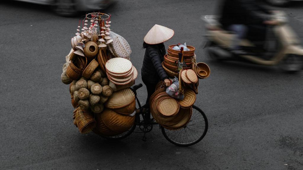 Una comerciante portando en bicicleta sus productos en Hanói (Vietnam).
