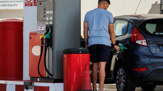 Un hombre echando carburante a su vehículo.