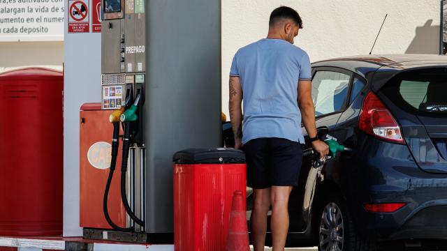 Un hombre echando carburante a su vehículo.