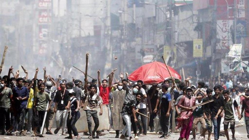 Decenas de ciudadanos de Bangladesh avanzan con palos y otros productos en una manifestación social.