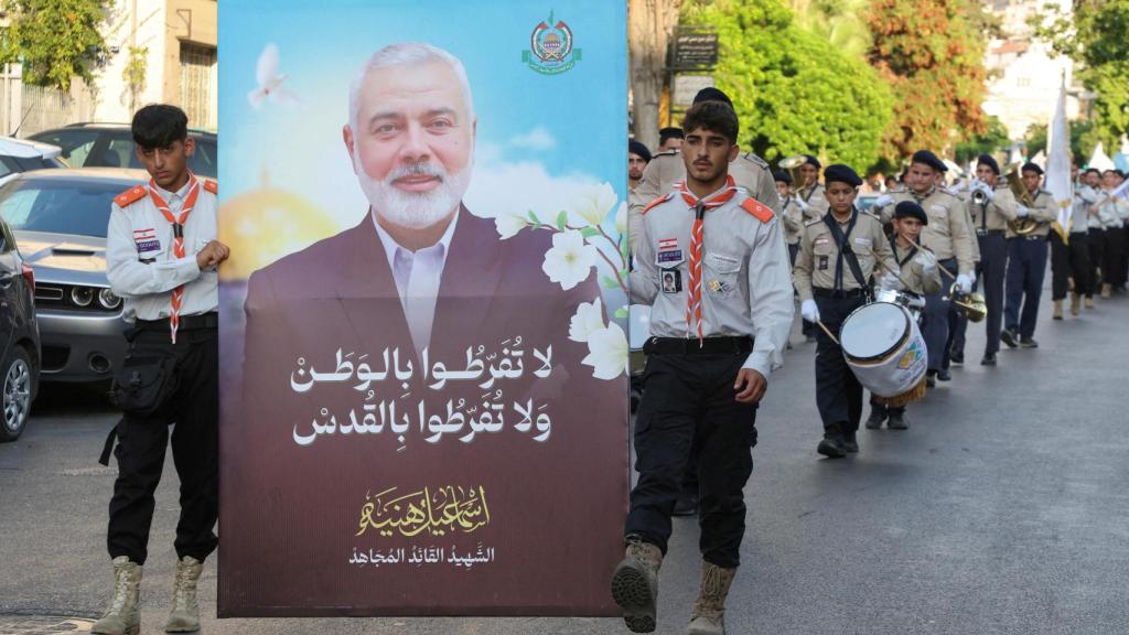 Miembros de los scouts Imam al-Mahdi llevan una imagen que representa al difunto líder de Hamás, Ismail Haniyeh, durante una protesta que condena su asesinato en el Líbano.