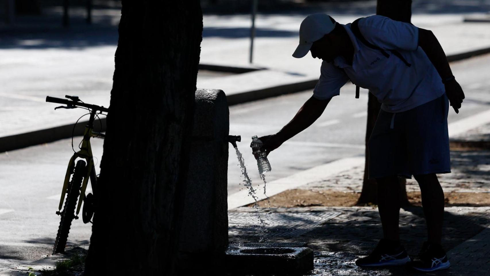 Un hombre rellena una botella de agua en una fuente.