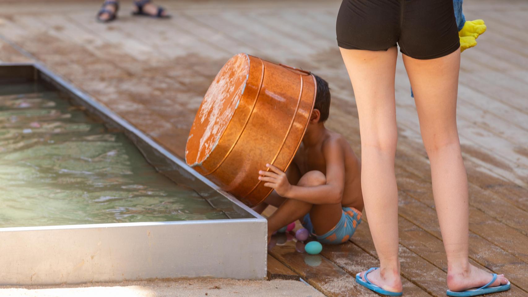 Un niño se tira agua de la fuente encima para protegerse del calor.