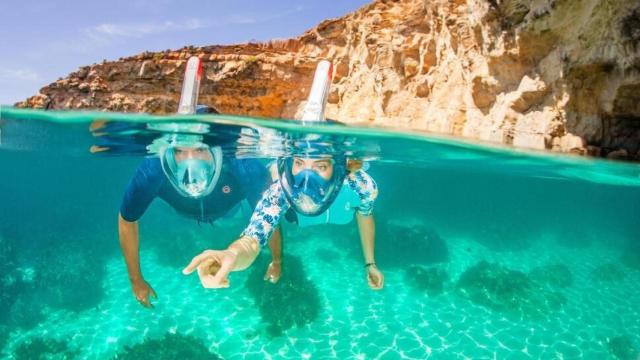 Dos personas practicando snorkel en aguas cristalinas.