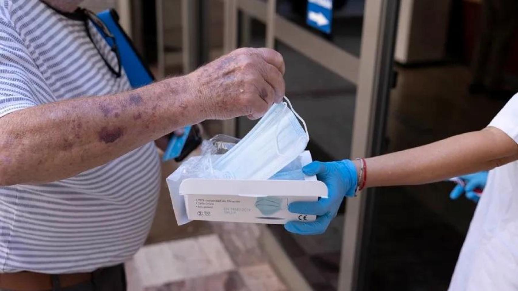 Una trabajadora de un centro de salud entrega una mascarilla a un paciente, en una imagen de archivo.