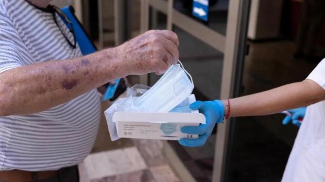 Una trabajadora de un centro de salud entrega una mascarilla a un paciente, en una imagen de archivo.