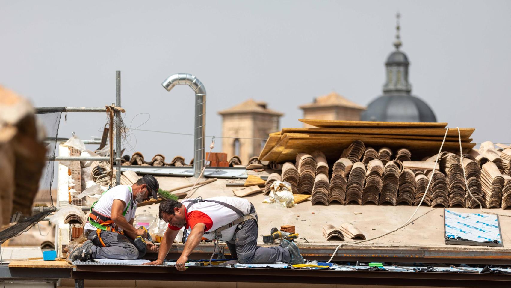 Unos obreros trabajan en el tejado de un edificio de Toledo.