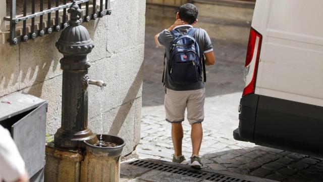 Un turista se refresca en una fuente de Toledo.